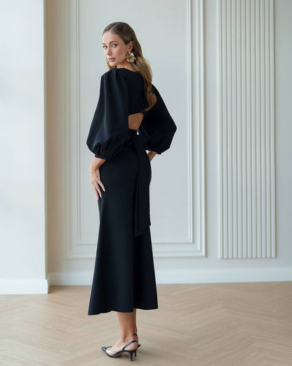 Woman wearing a black outfit with cut-out design in a minimalistic room.