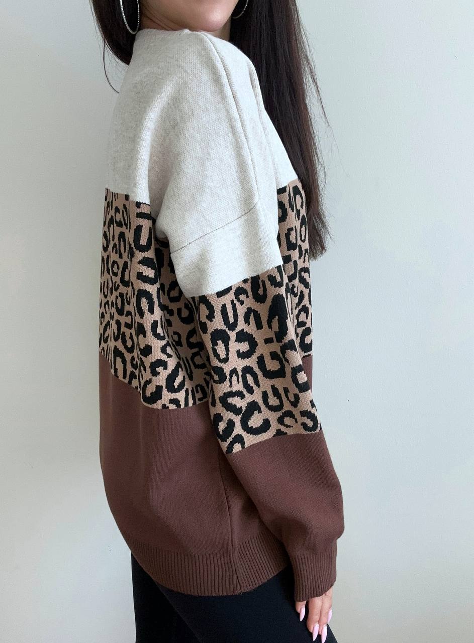 Person wearing a sweater with a leopard print pattern on a plain background