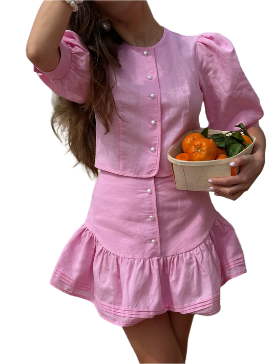 Person wearing a pink dress holding a basket of oranges on a white background