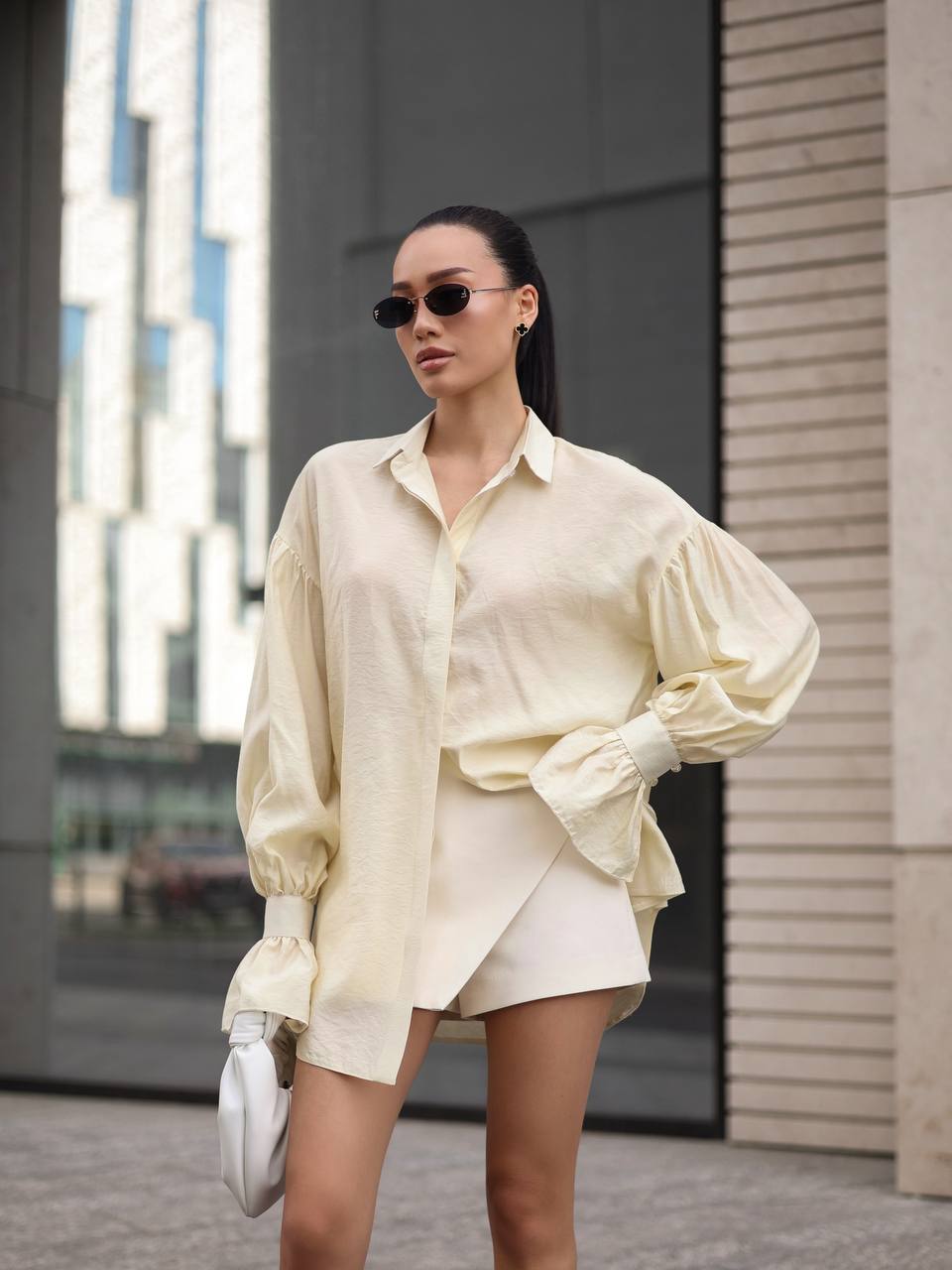 Woman wearing a light-colored outfit with sunglasses in an urban setting