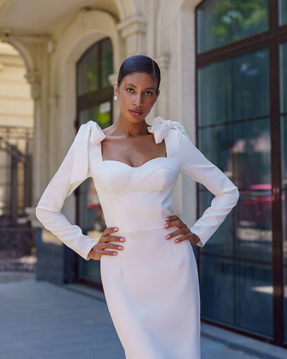Woman in a white dress standing in front of a building