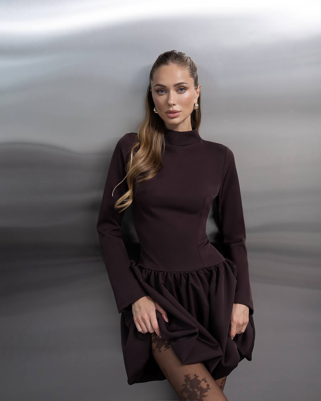 Woman wearing a brown dress against a gray background