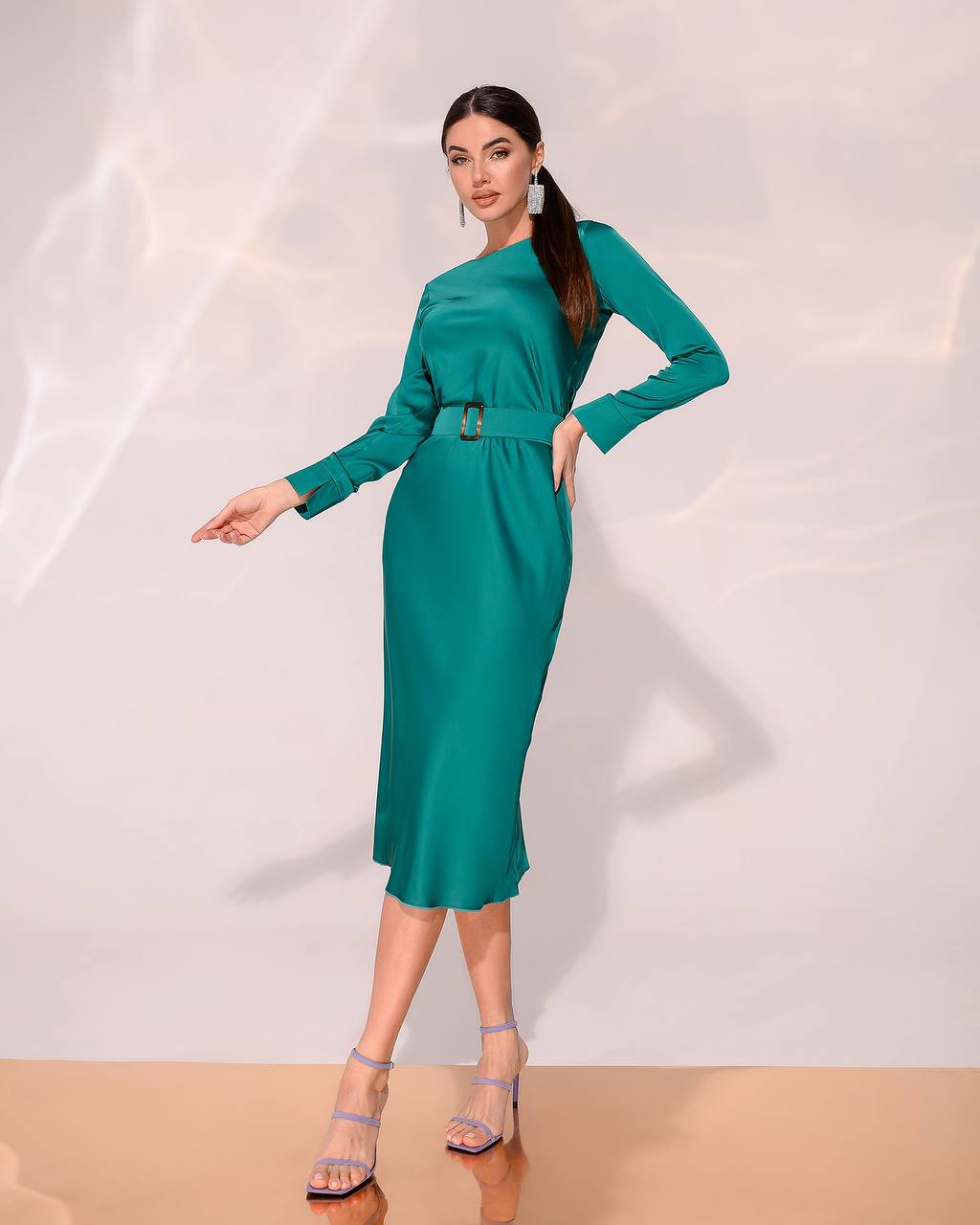 Woman wearing a teal dress against a white background