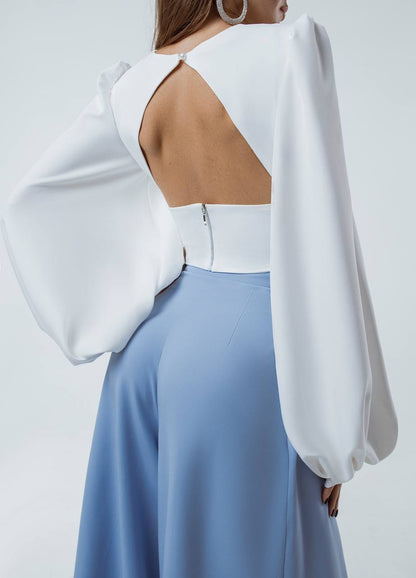 White blouse with cut-out design and light blue pants on a white background
