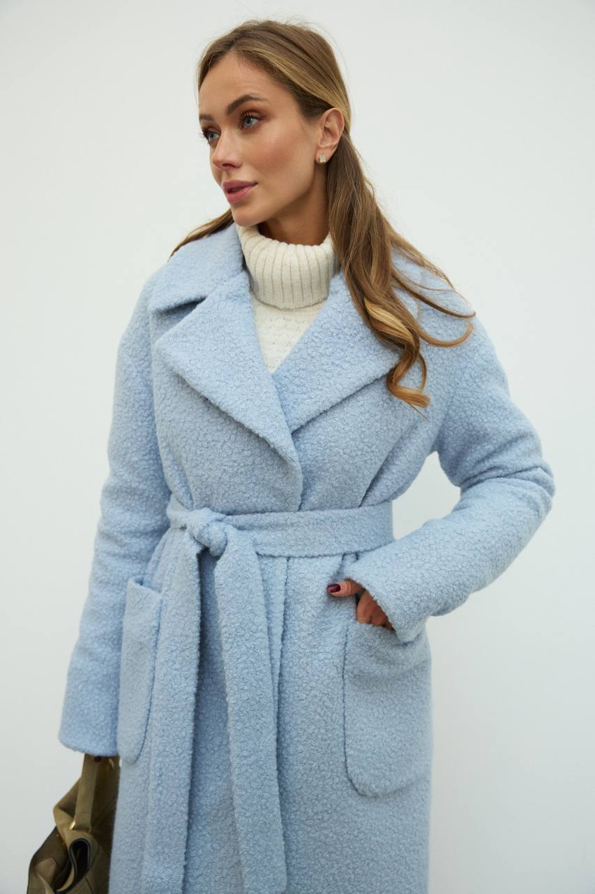 Woman wearing a light blue coat with a white background