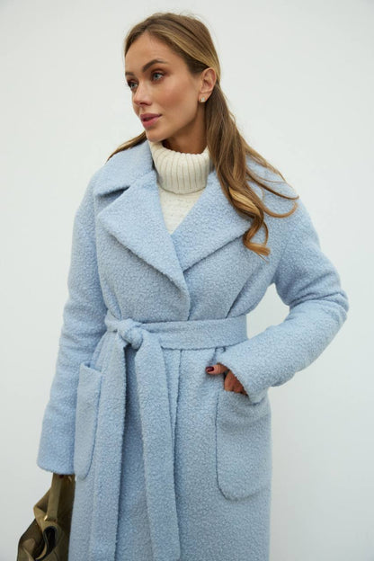 Woman wearing a light blue coat with a white background