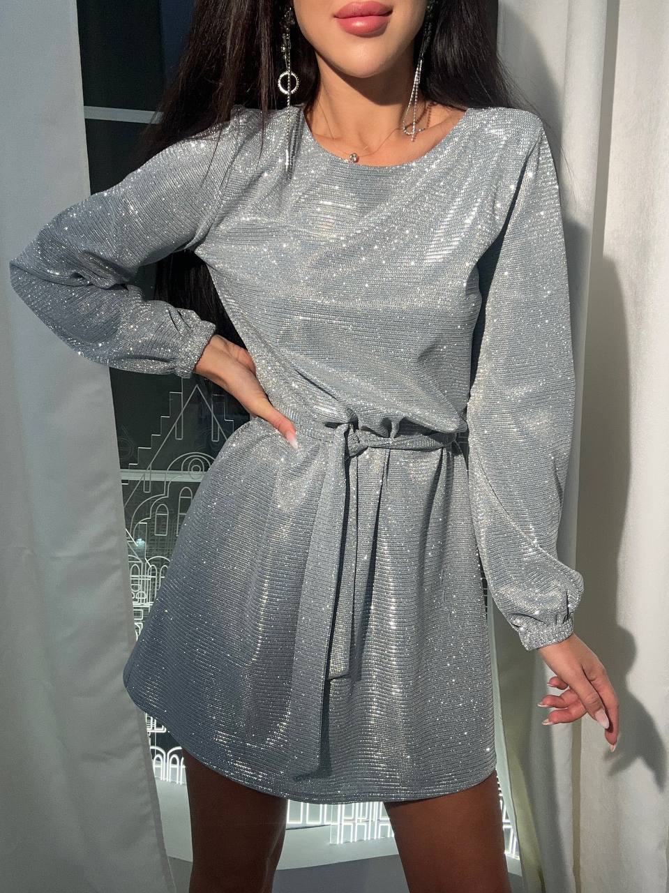 Woman wearing a silver sequin dress against a neutral background