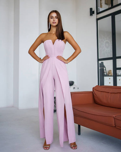 Woman wearing a pink strapless jumpsuit in a room with a brown sofa.