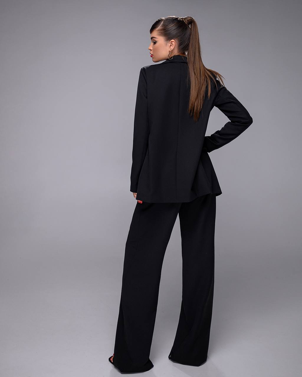 Woman wearing a black suit against a gray background