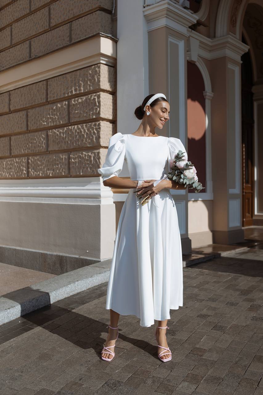 Woman in a white dress standing in front of a building