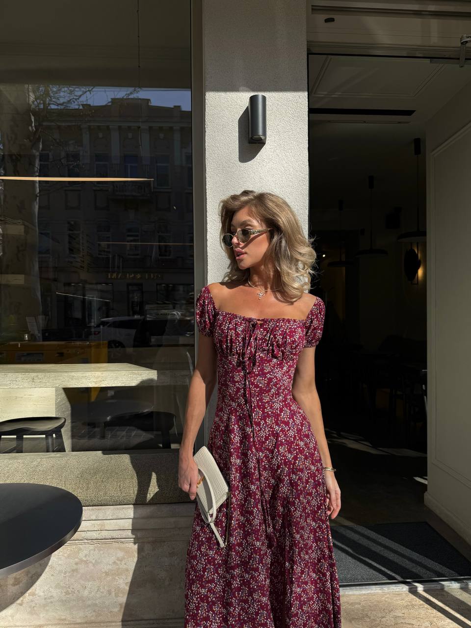 Woman in a floral dress standing outside a modern building