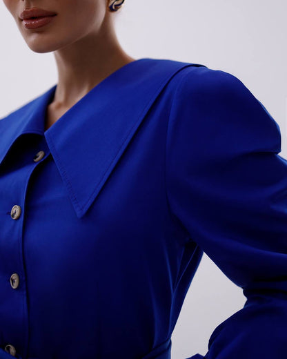 Close-up of a person wearing a blue shirt with a plain background