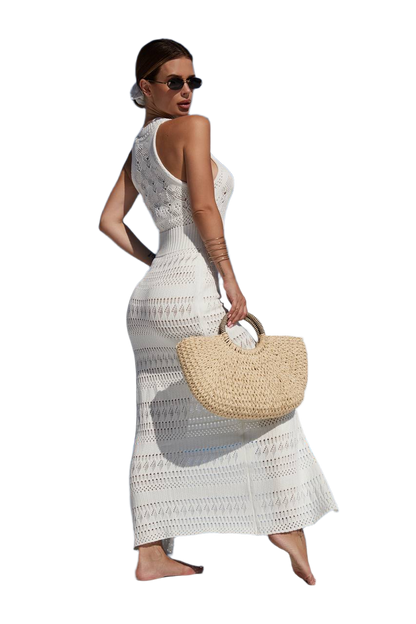 Woman in a white crochet dress holding a straw bag on a white background