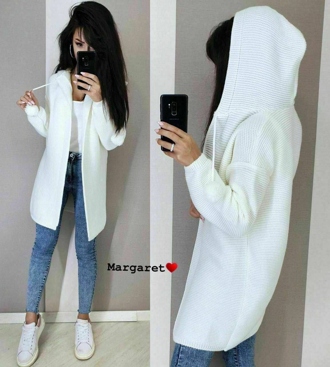 Person wearing a white hooded sweater and blue jeans, taking a mirror selfie.