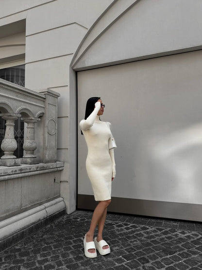 Woman in a white dress standing on a cobblestone street with a building in the background