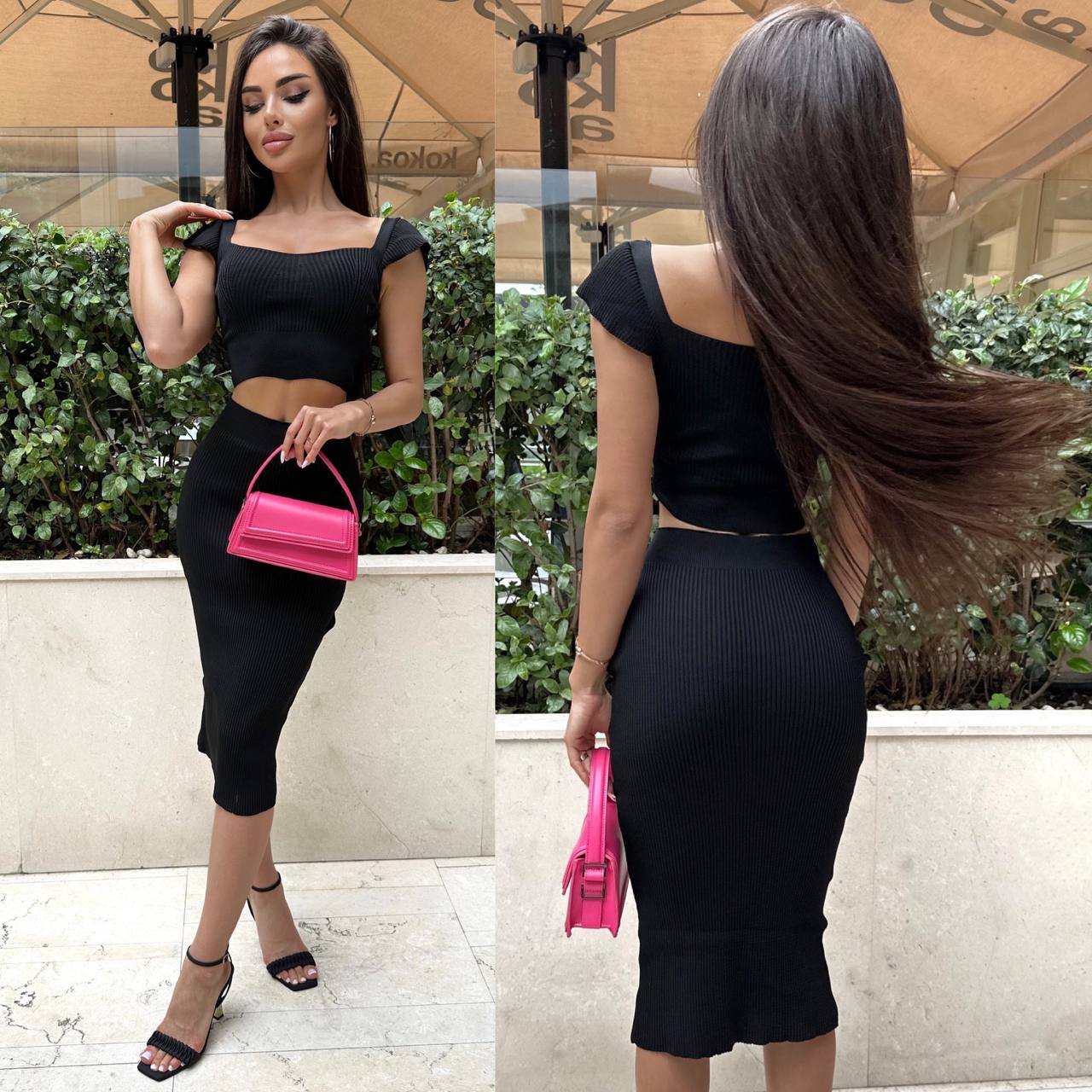 Woman in a black outfit holding a pink handbag, standing outdoors.