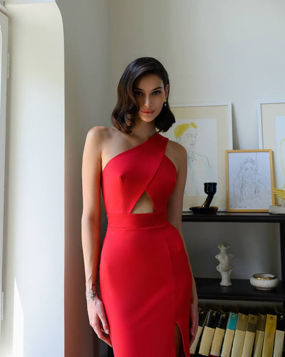 Woman in a red dress standing in a room with framed pictures on the wall.