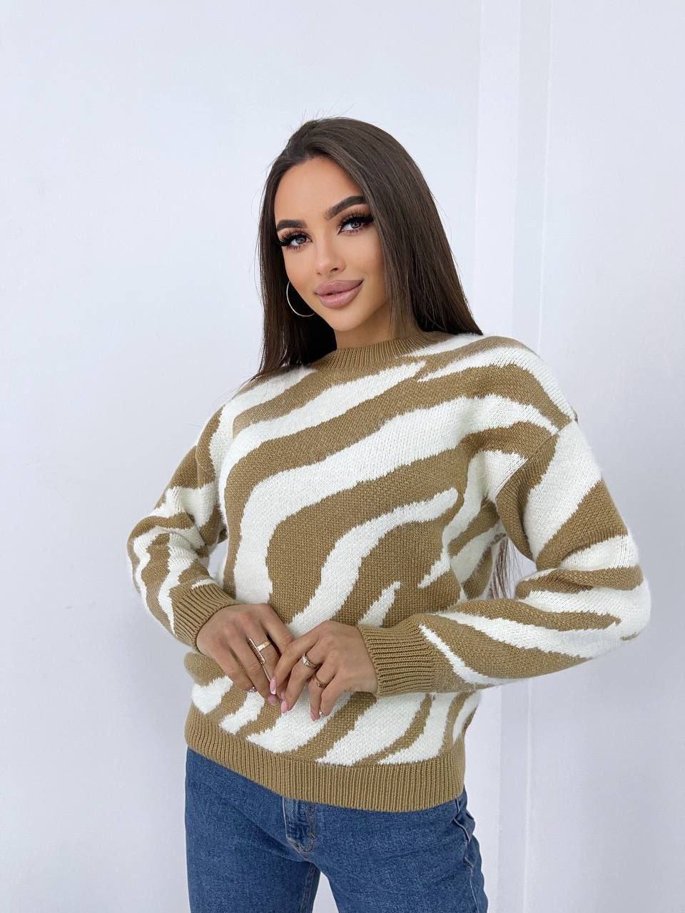 Woman wearing a brown and white patterned sweater against a plain background