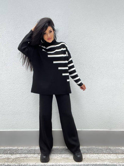 Person wearing a black and white striped sweater with a plain background