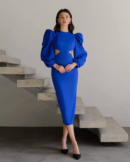 Woman in a blue dress standing on a staircase with a neutral background
