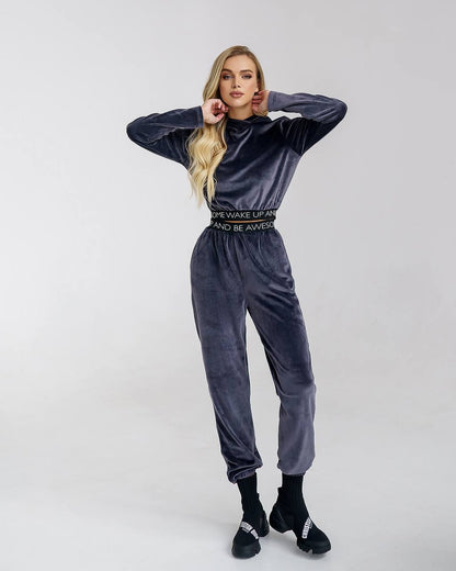 Woman wearing a gray velvet tracksuit with text on a white background