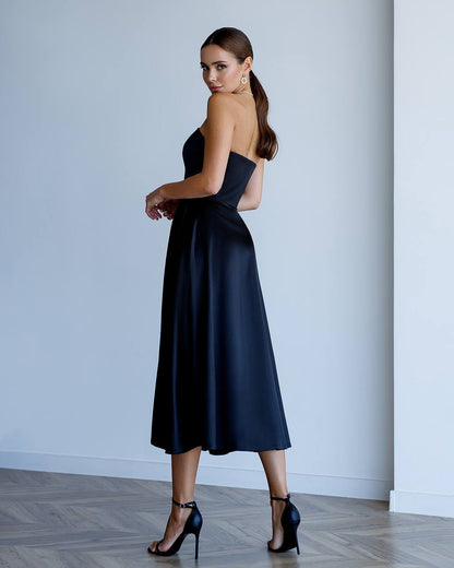 Woman wearing a black strapless dress against a plain background