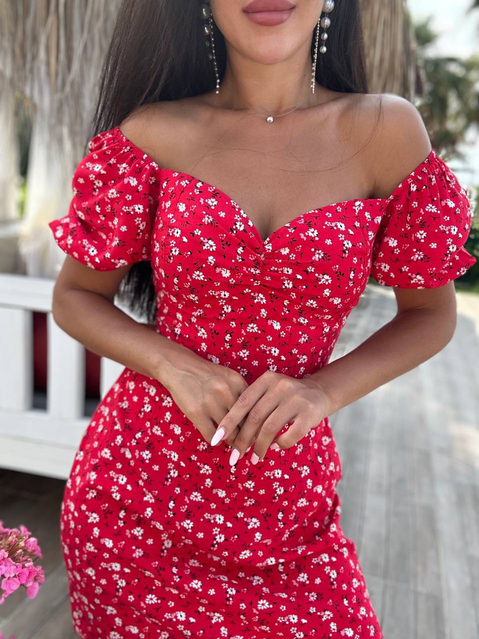 Woman wearing a red floral off-shoulder dress with blurred background