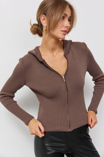 Woman wearing a brown zip-up hoodie against a white background