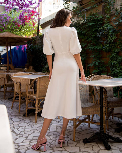 Woman in a white dress standing in an outdoor cafe setting