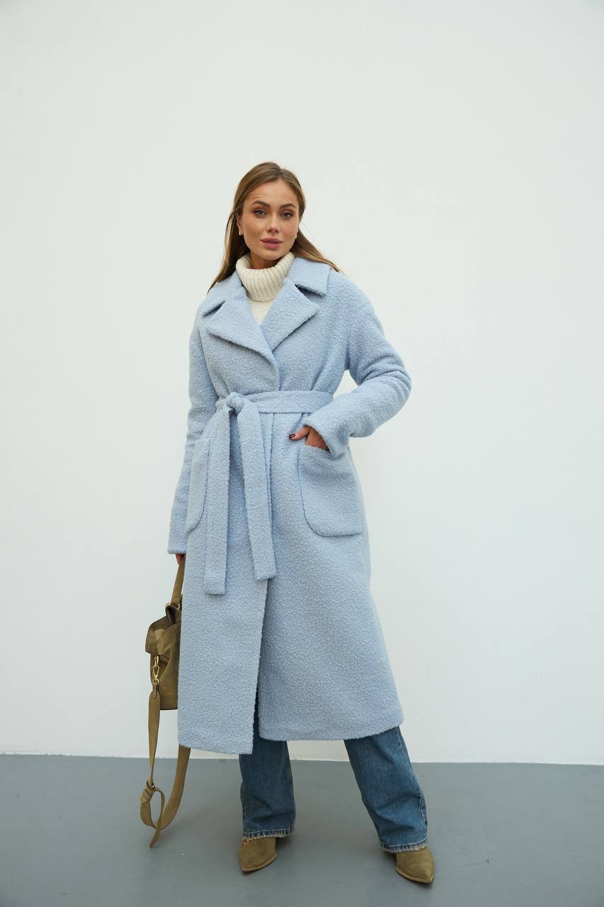 Woman wearing a light blue coat with a white background