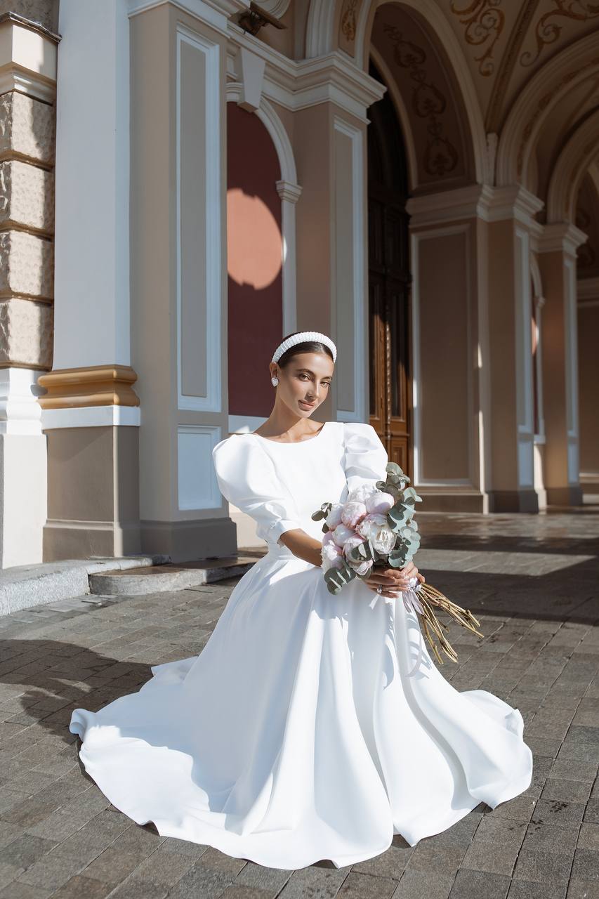 Woman in a white wedding dress holding flowers in an elegant indoor setting