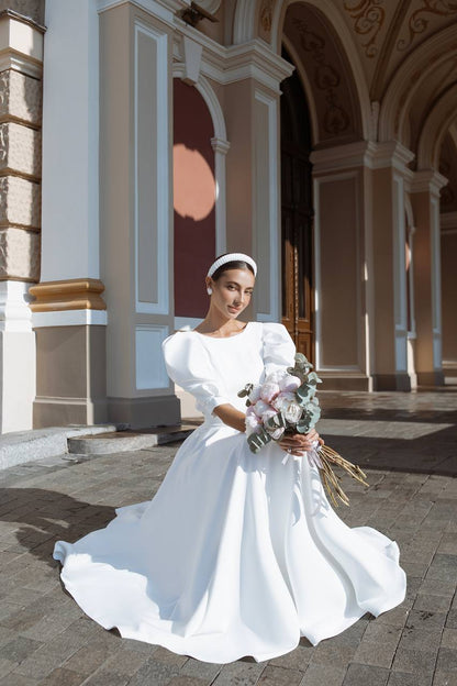 Woman in a white wedding dress holding flowers in an elegant indoor setting
