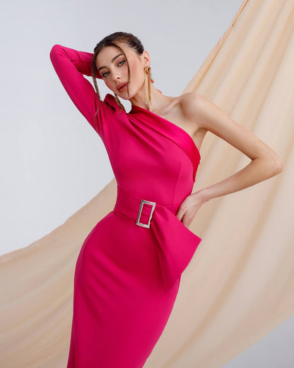 Woman wearing a bright pink one-shoulder dress with a belt against a beige and white background