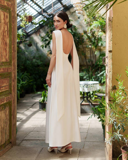 Woman in a white dress with a backless design standing in a greenhouse.