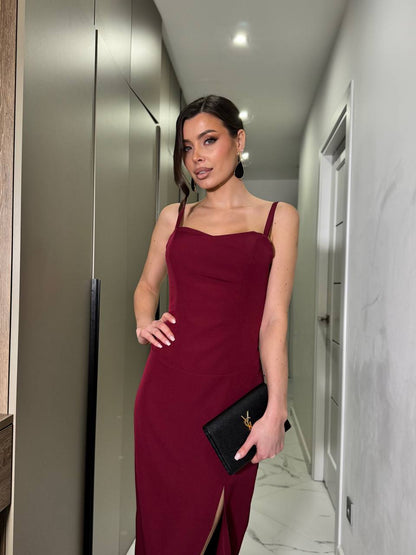 Woman in a burgundy dress holding a black clutch in an elevator.