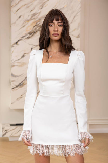 Woman wearing a white dress with lace details in a neutral setting