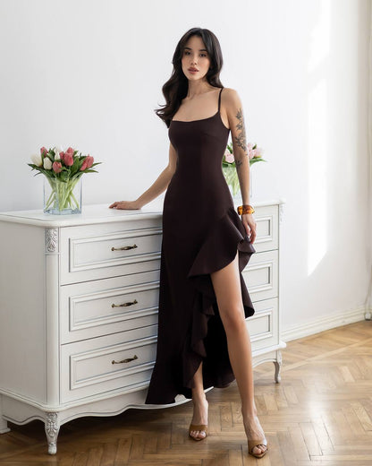Woman in a black dress standing in a room with white furniture and flowers.