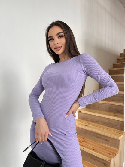 Woman in a purple dress standing in front of a staircase