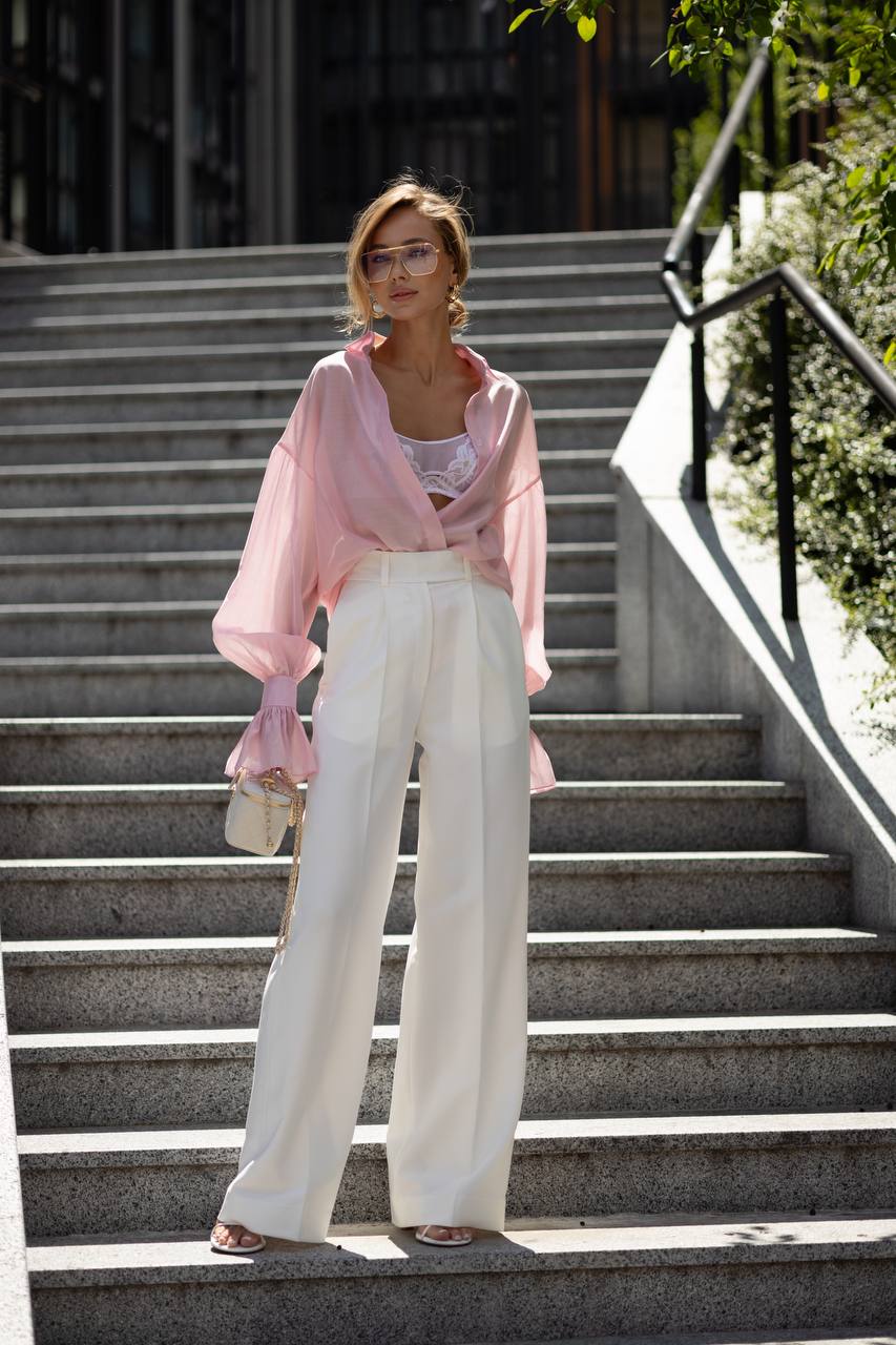 Woman in a pink top and white pants standing on outdoor steps.