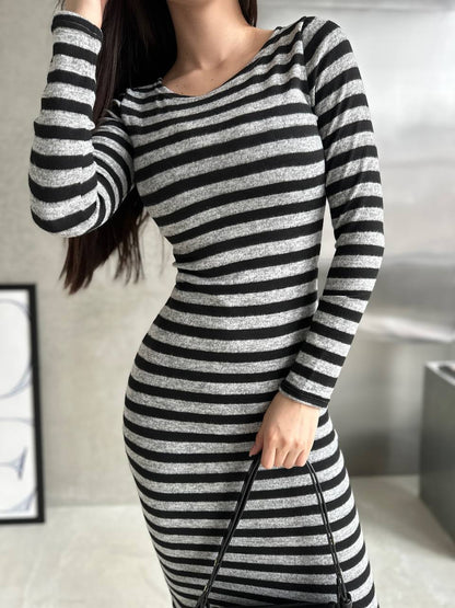 Person wearing a black and gray striped dress with a blurred background