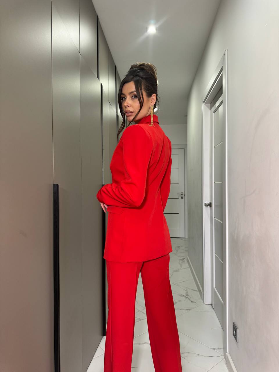 Person wearing a red outfit standing in a hallway.