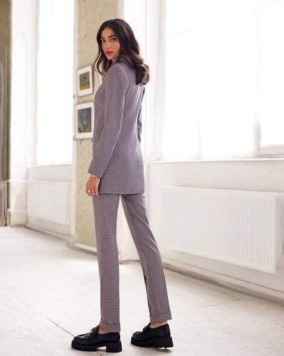 Woman wearing a gray checkered suit in a bright room.