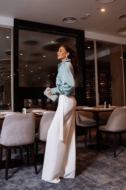 Woman in a stylish outfit standing in a modern restaurant.