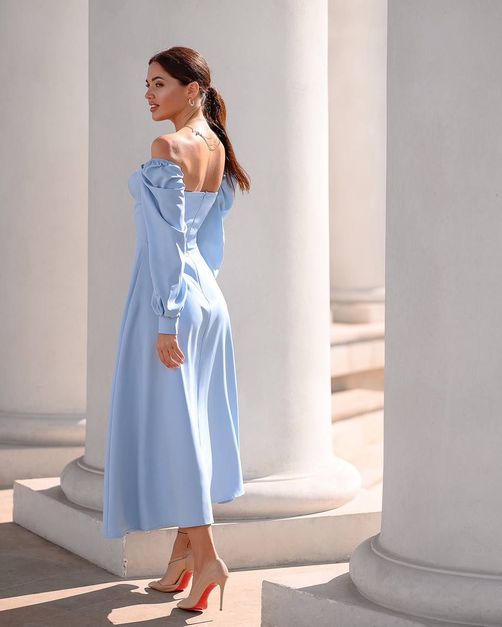 Woman in a light blue dress standing in front of classical columns