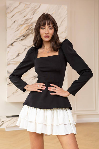Woman wearing a black top and white skirt with a neutral background