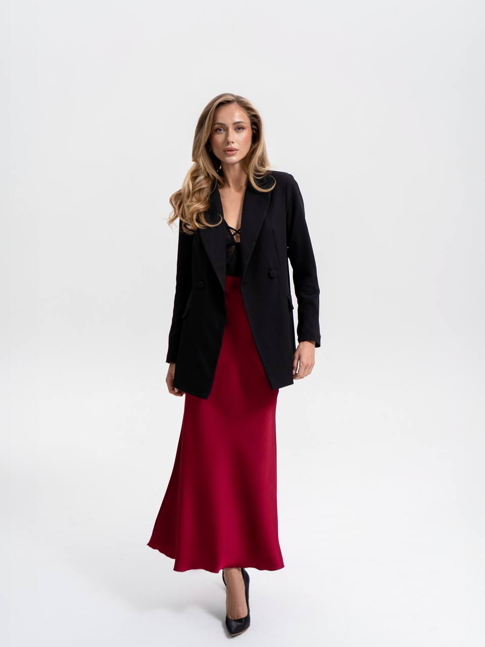 Woman wearing a black blazer over a red dress on a white background