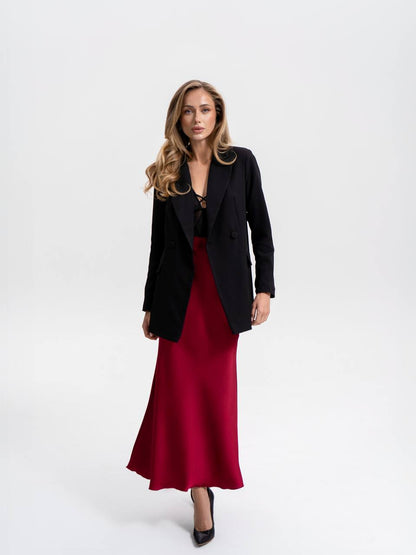 Woman wearing a black blazer over a red dress on a white background