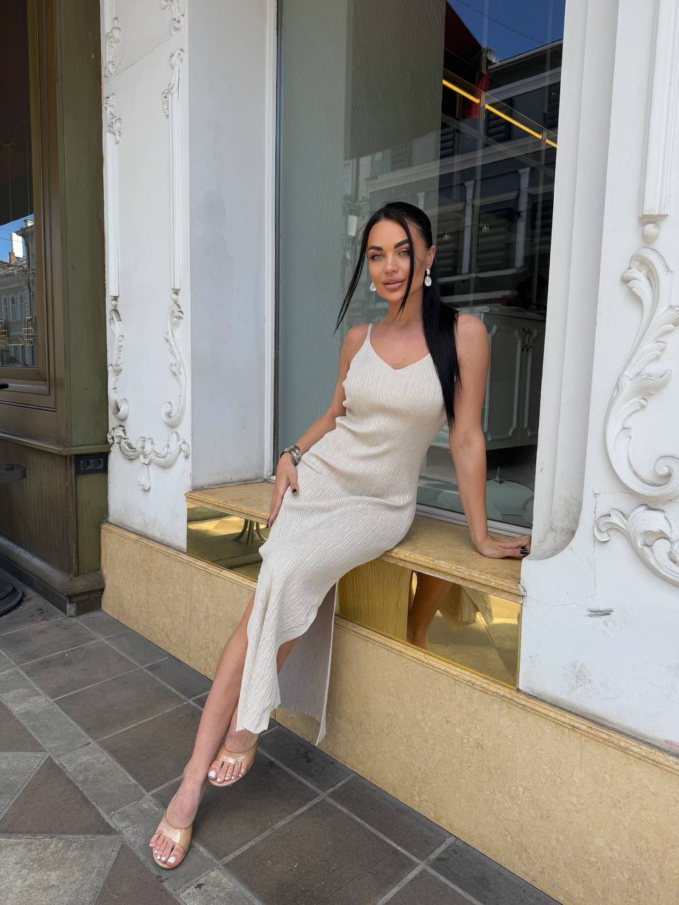 Woman in a white dress sitting on a ledge outside a building