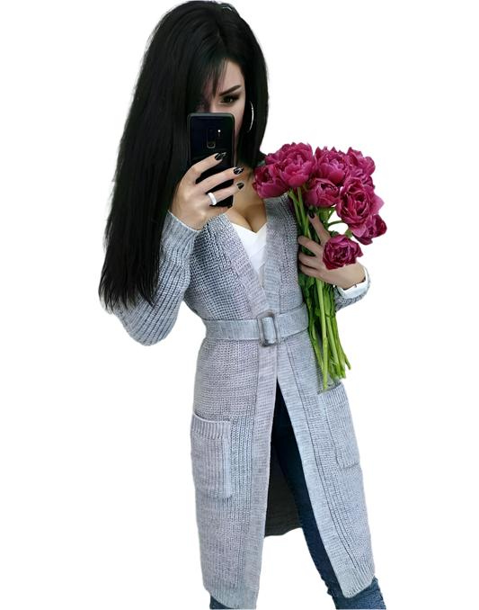 Woman in a gray coat holding pink flowers and a phone on a white background
