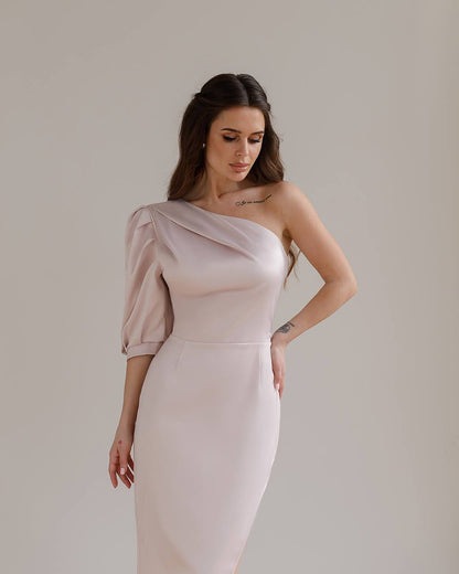 Woman wearing a one-shoulder dress against a plain background